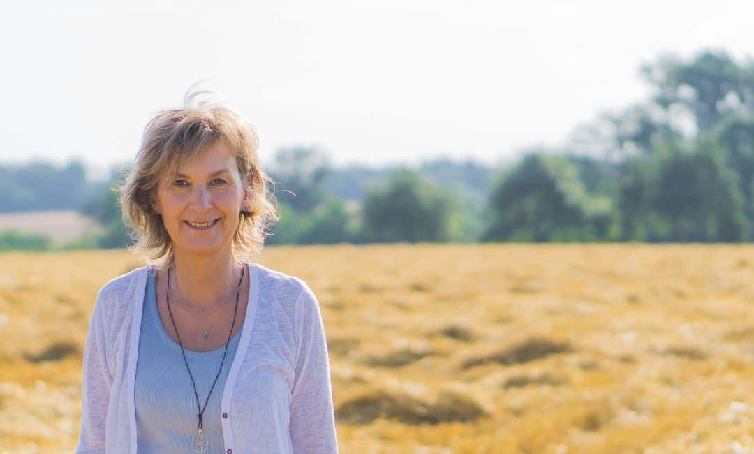 Header 15.04.2025 Martina Eyth steht vor einem abgemähtem Feld und lächelt in die Kamera.